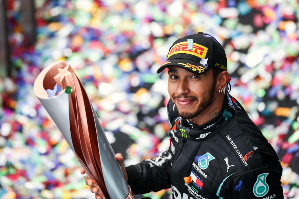 Un feliz Lewis Hamilton levantando el trofeo y mirando a la cámara
